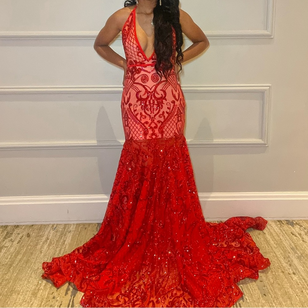 The dress features a halter neckline, an open back, and a long, lightweight